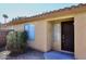 Tan home exterior showing the front door and small bushes and desert landscaping in front at 43857 W Bedford Dr, Maricopa, AZ 85138