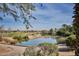 Scenic view of golf course and lake, complemented by lush greenery and vibrant landscaping at 43857 W Bedford Dr, Maricopa, AZ 85138