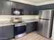 Modern kitchen features stainless steel appliances, granite countertops, and dark wood cabinets at 43857 W Bedford Dr, Maricopa, AZ 85138