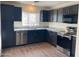 Modern kitchen features stainless steel appliances, granite countertops, and dark wood cabinets at 43857 W Bedford Dr, Maricopa, AZ 85138