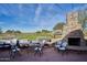 Cozy outdoor patio featuring a stone fireplace, table, chairs, and views of the golf course at 43857 W Bedford Dr, Maricopa, AZ 85138