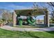 Covered playground with green play equipment and mature shade trees providing for a safe play area at 43857 W Bedford Dr, Maricopa, AZ 85138