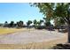 Outdoor sand volleyball court in a residential community, surrounded by lush greenery and trees at 43857 W Bedford Dr, Maricopa, AZ 85138