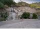 Scenic waterfall feature adds a natural touch to the property with vibrant flowers and lush greenery at 4550 E Foothill Dr, Paradise Valley, AZ 85253