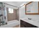 Bathroom featuring a shower-tub combo with tile surround, a window, and a vanity at 5338 N 21St Ave, Phoenix, AZ 85015