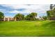 Community green space with manicured lawn, mature trees, and condos in the background on a sunny day at 9396 E Purdue Ave # 220, Scottsdale, AZ 85258
