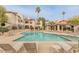 A view of the community pool and patio with lounge seating in front of multi-story condo buildings at 9396 E Purdue Ave # 220, Scottsdale, AZ 85258