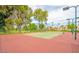 Exterior view of a tennis court with trees, green space, and condominiums in the background at 9396 E Purdue Ave # 220, Scottsdale, AZ 85258