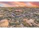 Expansive aerial view of desert homes surrounded by natural rock formations and mountains under colorful sunset skies at 10671 E Hedgehog Pl, Scottsdale, AZ 85262