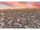 Panoramic aerial shot featuring luxury homes scattered across desert landscape, with a mountain backdrop under a sunset sky at 10671 E Hedgehog Pl, Scottsdale, AZ 85262
