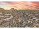 Bird's-eye view of desert homes, featuring a golf course and mountains, sunset enhancing overall appeal at 10671 E Hedgehog Pl, Scottsdale, AZ 85262