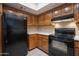 Well-lit kitchen features wood cabinets, neutral countertops, and black appliances, including refrigerator and oven at 12212 N Paradise Village Pkwy # 308, Phoenix, AZ 85032