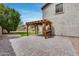 A large backyard features a brick-paved patio with a wooden pergola, a green lawn and partial house view at 14333 W Lexington Ave, Goodyear, AZ 85395