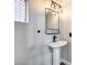 Stylish bathroom features a modern pedestal sink, unique lighting, and a functional mirror at 14333 W Lexington Ave, Goodyear, AZ 85395