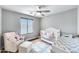 Charming Bedroom with a white crib, plush chair, and ceiling fan at 14333 W Lexington Ave, Goodyear, AZ 85395
