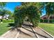A picturesque garden path with a vibrant floral archway and trimmed bushes for a serene outdoor experience at 14333 W Lexington Ave, Goodyear, AZ 85395