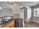 Kitchen sink with faucet, stainless steel dishwasher, wooden cabinets, and tile backsplash, with a view into dining area at 14333 W Lexington Ave, Goodyear, AZ 85395