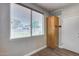 Room with a window with blinds, a tall wooden cabinet, a door, and light gray walls at 14333 W Lexington Ave, Goodyear, AZ 85395