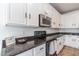 A modern kitchen features white cabinets, stainless steel appliances and dark granite countertops at 22065 W Twilight Trl, Buckeye, AZ 85326