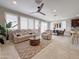 Bright living room with tile floors and fan with plush seating, seamlessly connects the kitchen with an island and dining area at 22902 E Arroyo Verde Dr, Queen Creek, AZ 85142