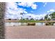 Scenic community view featuring a tranquil lake, lush green grass, palm trees, and blue sky with clouds at 2563 N Doral Cir, Mesa, AZ 85215