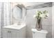Bright bathroom featuring a vanity with white cabinetry, a round mirror, and a shower with a patterned curtain at 3009 N 81St Ln, Phoenix, AZ 85033