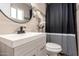Modern bathroom with stylish sink, decorative mirror, tiled walls, and shower with decorative curtains at 3009 N 81St Ln, Phoenix, AZ 85033
