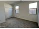 Bright bedroom featuring two windows, neutral carpet, and closet with sliding doors at 3481 S 175Th Ln, Goodyear, AZ 85338