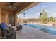 Inviting covered patio with outdoor seating, adjacent to a sparkling pool and landscaped backyard at 3816 E Rakestraw Ln, Gilbert, AZ 85298