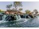 Community entrance with a waterfall, rock landscaping, and community sign, nestled among mature trees and flowering plants at 3816 E Rakestraw Ln, Gilbert, AZ 85298