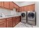 Spacious laundry room with wooden cabinets, countertop, sink, and modern washer and dryer at 3816 E Rakestraw Ln, Gilbert, AZ 85298