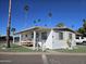 Charming home with a covered porch, desert landscaping, and mature palm trees at 4065 E University Dr # 83, Mesa, AZ 85205