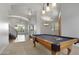 Bright game room boasts a wooden pool table beneath decorative lighting, adjacent to a staircase and open-concept living space at 4235 W Harrison St, Chandler, AZ 85226