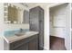 Bathroom with a decorative mirror, granite countertop and a dark-toned cabinet and a walk-in closet nearby at 43815 W Cahill Dr, Maricopa, AZ 85138