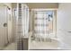 Bright bathroom featuring a shower-tub combination, a large window, and a striped shower curtain at 43815 W Cahill Dr, Maricopa, AZ 85138