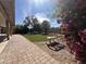 Beautifully landscaped backyard with a brick walkway, mature trees, and flowering bushes at 4615 E Emerald Ave, Mesa, AZ 85206