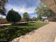 Manicured backyard with mature shade trees, green grass, and brick-paved walkway at 4615 E Emerald Ave, Mesa, AZ 85206