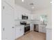 Modern white kitchen with stainless steel appliances, quartz countertops, and wood-look flooring at 463 W Taylor Ave, Coolidge, AZ 85128
