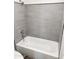 Updated bathroom with gray tiled shower and a white bathtub at 5987 N 48Th Dr, Glendale, AZ 85301
