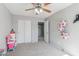 Bright bedroom featuring neutral walls and carpet, ceiling fan, and closet with white bi-fold doors at 7038 W Beverly Rd, Laveen, AZ 85339