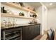 Home bar area equipped with a wine fridge, marble countertops, and shelving with decorative items at 7175 E Camelback Rd # 401, Scottsdale, AZ 85251