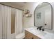 Bright bathroom features a shower with curtain, single sink vanity, framed mirror, and decorative shelves at 7252 E Nido Ave, Mesa, AZ 85209