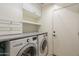 Well-lit laundry room featuring a washer, dryer, storage cabinets, and shelving at 7252 E Nido Ave, Mesa, AZ 85209