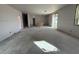 Spacious unfinished living room showing bare walls, concrete floor, staircase access and a window with view at 9613 W Parkway Dr, Tolleson, AZ 85353