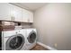 Well-equipped laundry room with a washer, dryer, and upper cabinets for convenient storage and functionality at 9705 E Mountain View Rd # 1143, Scottsdale, AZ 85258