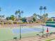 Nicely landscaped tennis court with blue and green surface, palm trees, and nearby community buildings at 9705 E Mountain View Rd # 1143, Scottsdale, AZ 85258