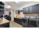 Functional laundry room with black cabinets, counter space, and modern washer/dryer units at 12734 W Crestvale Dr, Peoria, AZ 85383