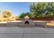 Backyard showcasing a built-in outdoor fireplace with seating and mature trees at 13007 W Tuckey Ct, Glendale, AZ 85307