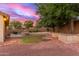 Beautiful backyard featuring a built-in fireplace, green grass and desert landscaping under a colorful twilight sky at 13007 W Tuckey Ct, Glendale, AZ 85307