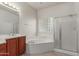 Well-lit bathroom featuring a soaking tub, glass block window, and tiled floor at 13007 W Tuckey Ct, Glendale, AZ 85307